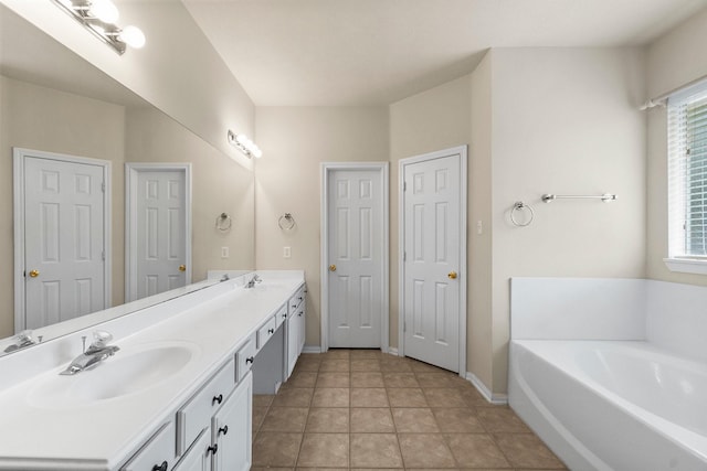 bathroom with baseboards, double vanity, a sink, tile patterned floors, and a bath