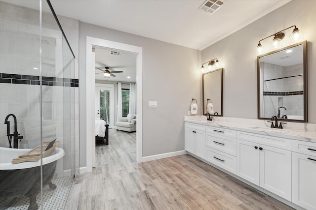 ensuite bathroom featuring double vanity, visible vents, wood finished floors, a shower stall, and a sink