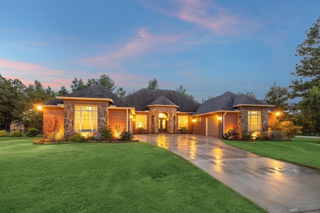 view of front of home with a garage, stone siding, a yard, and driveway