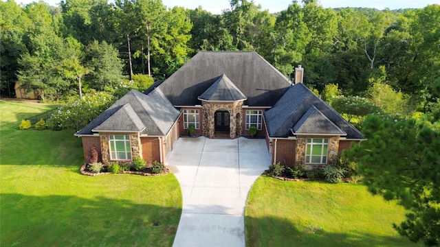 view of front of home featuring brick siding, stone siding, concrete driveway, a chimney, and a front yard