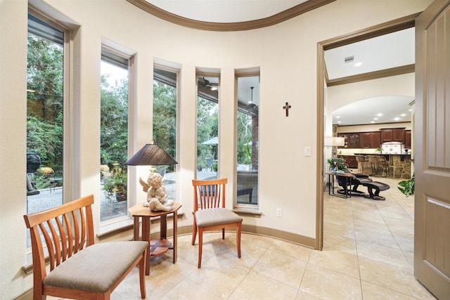 living area featuring arched walkways, light tile patterned flooring, visible vents, baseboards, and ornamental molding