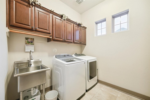 washroom featuring washing machine and dryer, a sink, visible vents, baseboards, and cabinet space