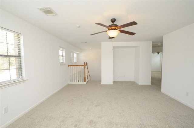 spare room with light carpet, visible vents, ceiling fan, and baseboards