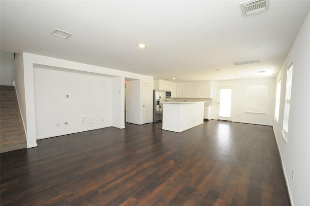 unfurnished living room with visible vents, recessed lighting, stairs, and dark wood-style flooring