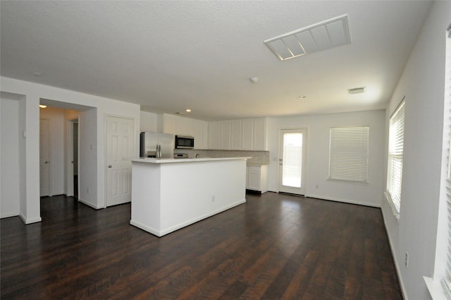 kitchen with visible vents, dark wood finished floors, a center island, appliances with stainless steel finishes, and white cabinets