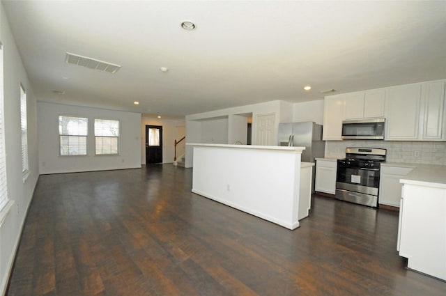 kitchen with visible vents, backsplash, dark wood finished floors, light countertops, and stainless steel appliances