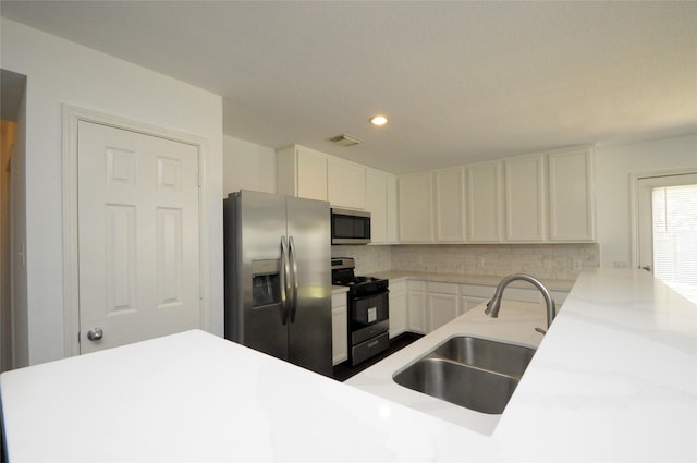 kitchen featuring tasteful backsplash, visible vents, light countertops, stainless steel appliances, and a sink