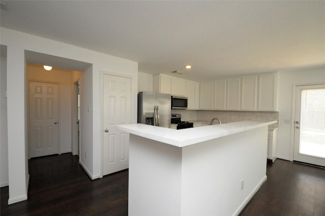 kitchen with dark wood-style flooring, decorative backsplash, light countertops, appliances with stainless steel finishes, and white cabinetry