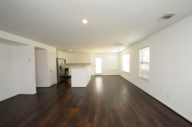 unfurnished living room featuring dark wood finished floors, baseboards, and visible vents