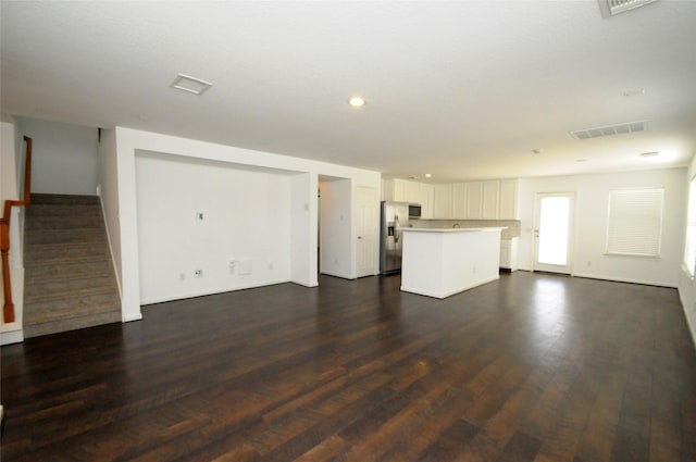 unfurnished living room with recessed lighting, visible vents, dark wood-type flooring, and stairs