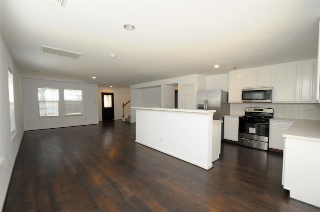 kitchen featuring visible vents, stainless steel appliances, light countertops, decorative backsplash, and dark wood-style flooring