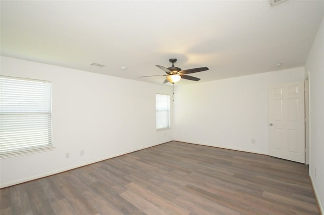 empty room with baseboards, wood finished floors, visible vents, and ceiling fan