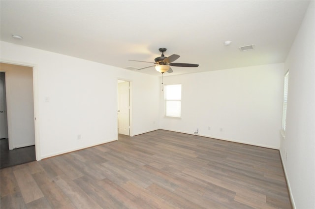 spare room featuring ceiling fan, visible vents, baseboards, and wood finished floors