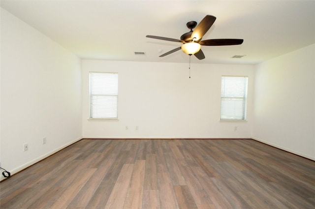 spare room featuring a ceiling fan, wood finished floors, visible vents, and baseboards