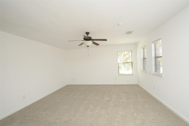 empty room featuring visible vents, baseboards, light colored carpet, and ceiling fan