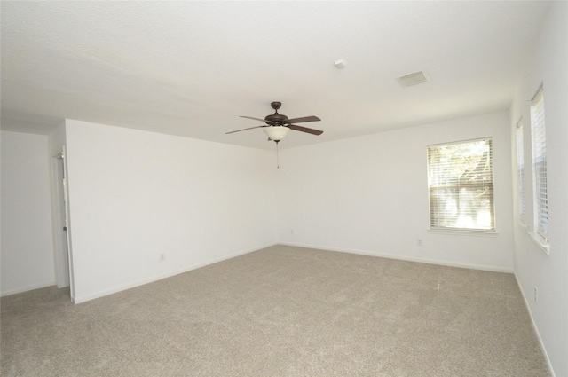 unfurnished room featuring light carpet, visible vents, a ceiling fan, and baseboards