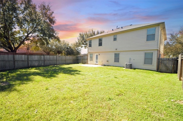 rear view of house featuring a patio area, central air condition unit, a lawn, and a fenced backyard