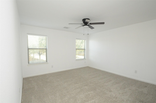 spare room featuring a ceiling fan, baseboards, visible vents, and light carpet