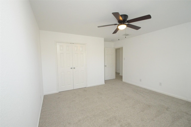 unfurnished bedroom with ceiling fan, baseboards, a closet, and light carpet