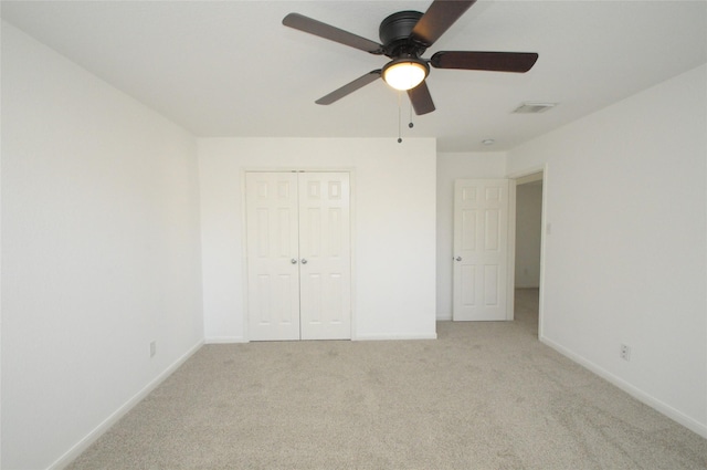 unfurnished bedroom featuring visible vents, baseboards, light carpet, a closet, and a ceiling fan