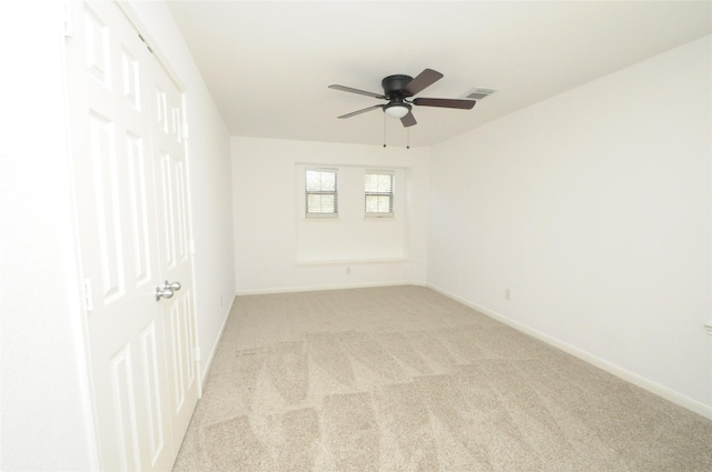 unfurnished room featuring visible vents, light colored carpet, baseboards, and ceiling fan