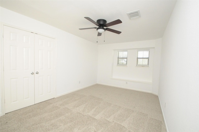 carpeted empty room with visible vents, baseboards, and a ceiling fan