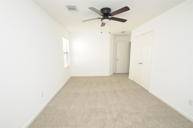 spare room with visible vents, light carpet, baseboards, and a ceiling fan