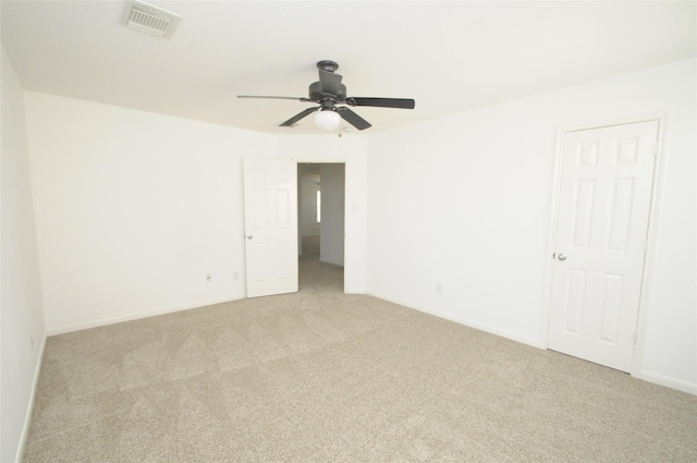 empty room featuring ceiling fan, light colored carpet, visible vents, and baseboards