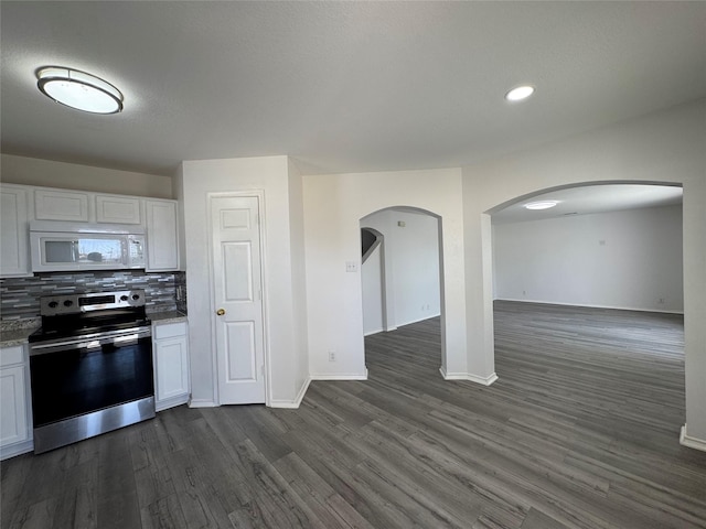 kitchen featuring arched walkways, decorative backsplash, dark wood finished floors, white microwave, and stainless steel electric stove