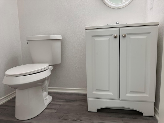 bathroom with toilet, baseboards, and wood finished floors