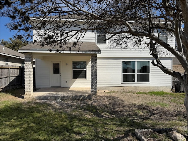 rear view of house with a yard, a shingled roof, fence, and a patio