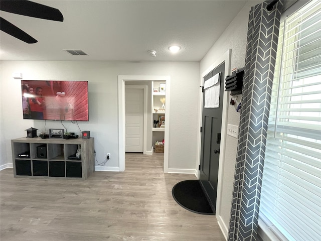 interior space featuring ceiling fan, a textured ceiling, wood finished floors, visible vents, and baseboards