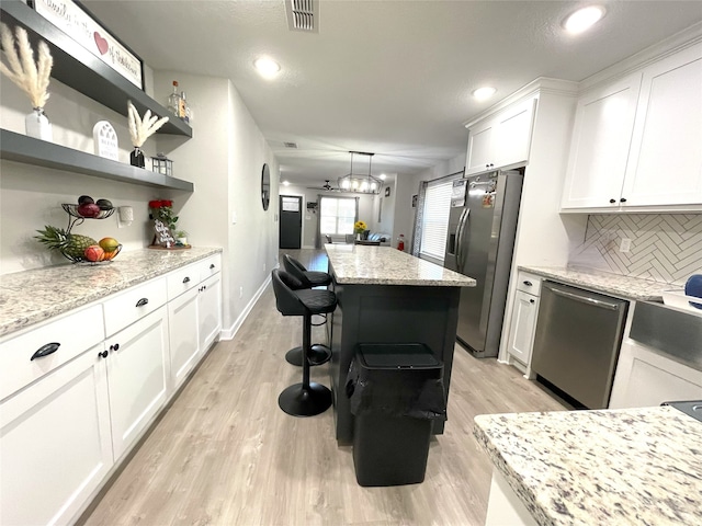 kitchen featuring appliances with stainless steel finishes, white cabinets, visible vents, and open shelves