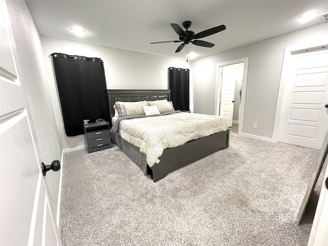 carpeted bedroom with ensuite bathroom, a ceiling fan, visible vents, and baseboards