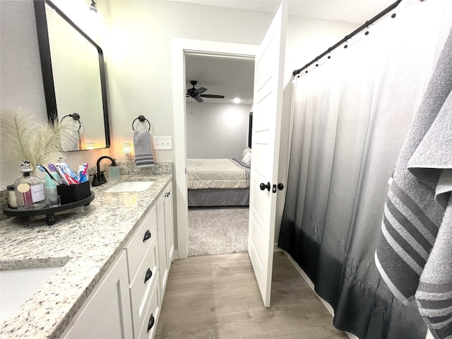 full bath featuring double vanity, connected bathroom, a ceiling fan, wood finished floors, and a sink