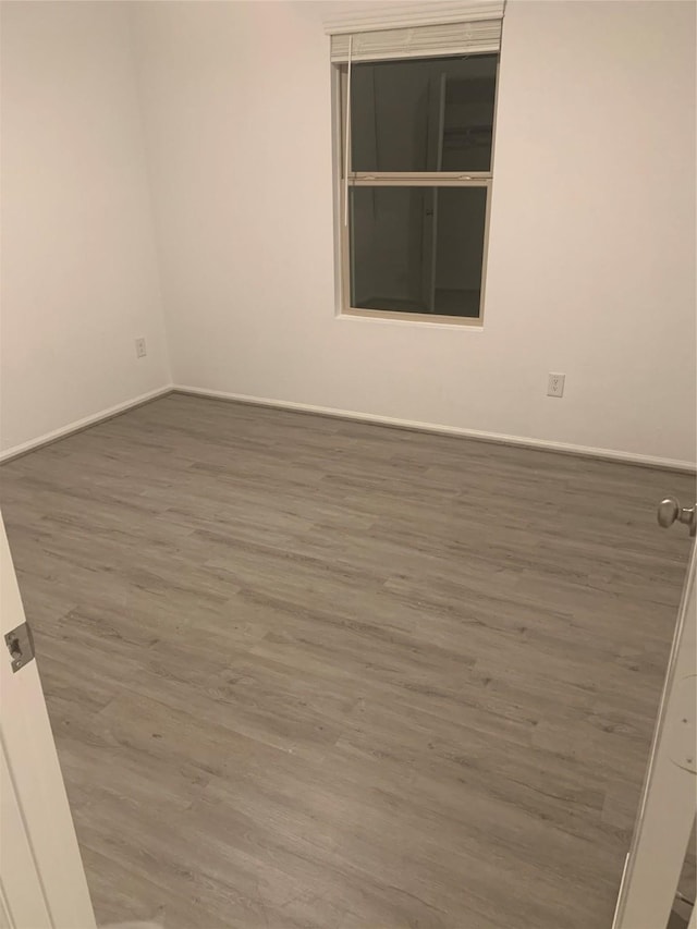 empty room with baseboards and wood finished floors