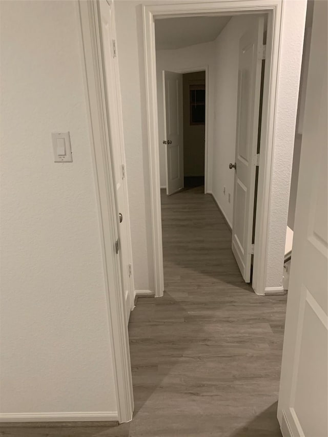 corridor featuring baseboards and wood finished floors