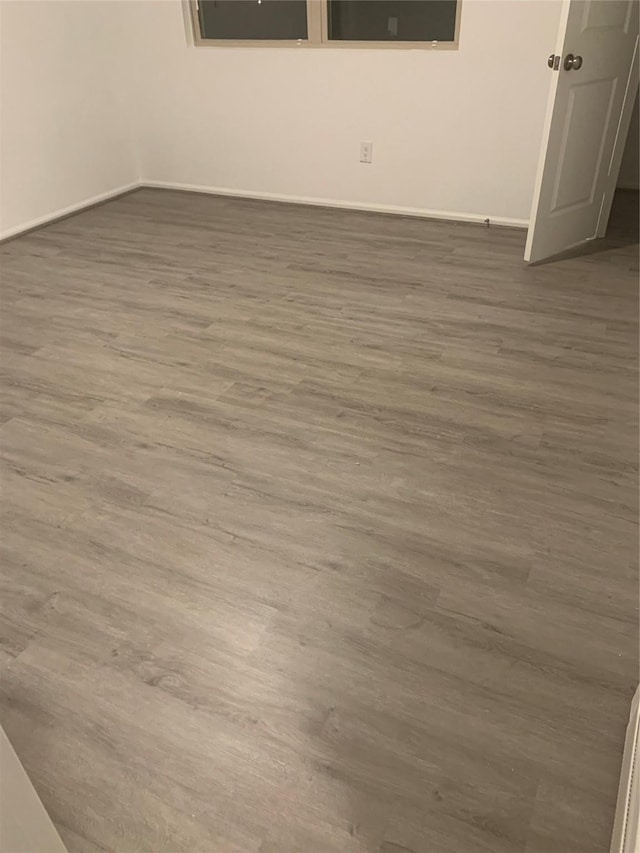 spare room with baseboards and wood finished floors