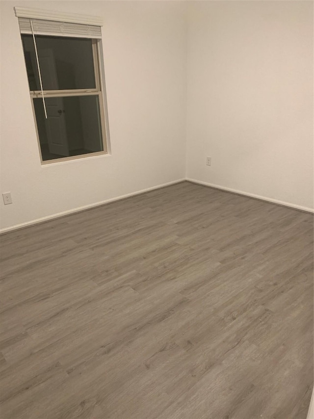 spare room featuring baseboards and wood finished floors