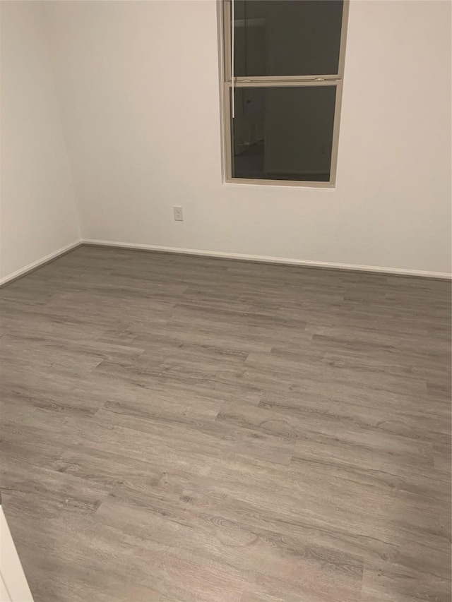 unfurnished room with baseboards and wood finished floors