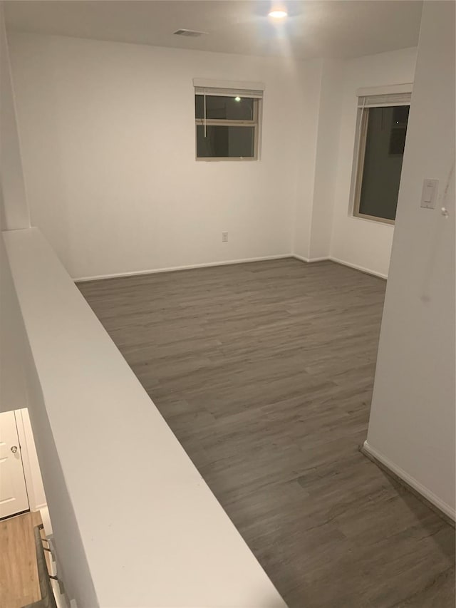 spare room with baseboards and wood finished floors