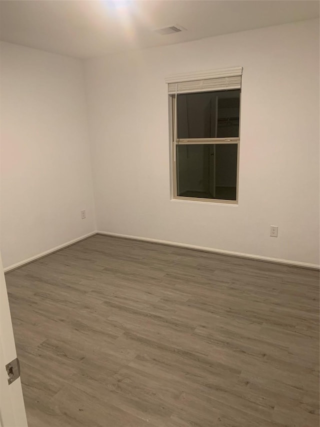 spare room featuring visible vents, baseboards, and wood finished floors