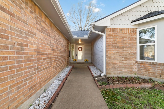 property entrance featuring brick siding and roof with shingles