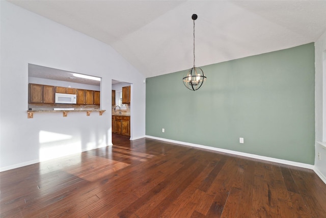 unfurnished living room with baseboards, lofted ceiling, dark wood-style flooring, a notable chandelier, and a sink