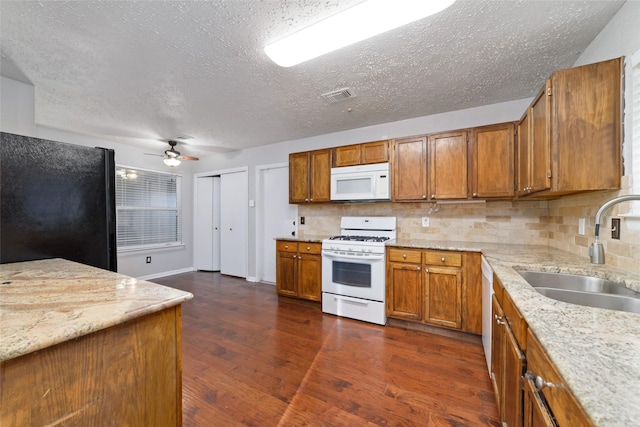 kitchen featuring white appliances, dark wood-style floors, brown cabinetry, and a sink