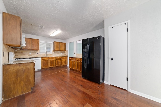 kitchen with white appliances, visible vents, brown cabinets, dark wood-style flooring, and tasteful backsplash