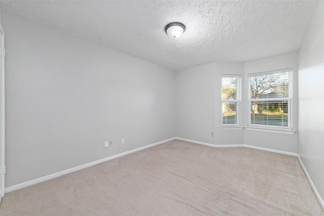 unfurnished room featuring light colored carpet, baseboards, and a textured ceiling