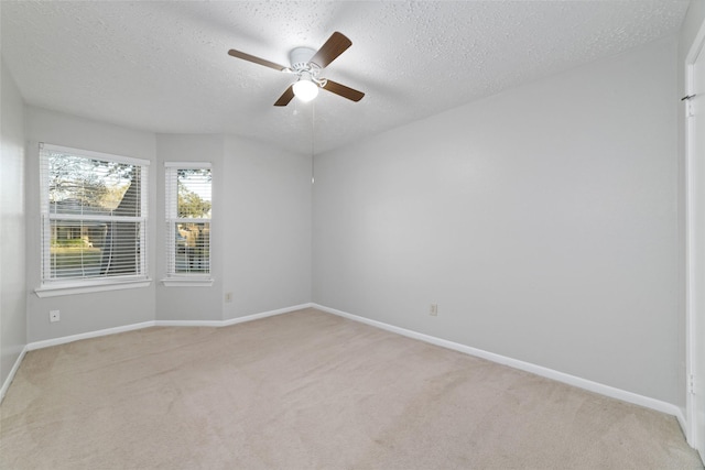 unfurnished room featuring a ceiling fan, light colored carpet, baseboards, and a textured ceiling