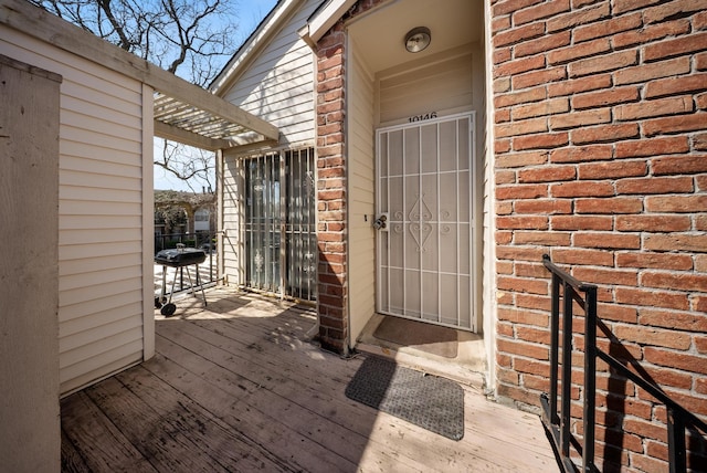 view of exterior entry with brick siding and a deck