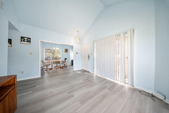 interior space with baseboards, visible vents, a chandelier, light wood-style floors, and high vaulted ceiling